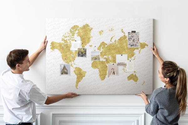 Lavagna di sughero con mappa del mondo dorata su sfondo bianco