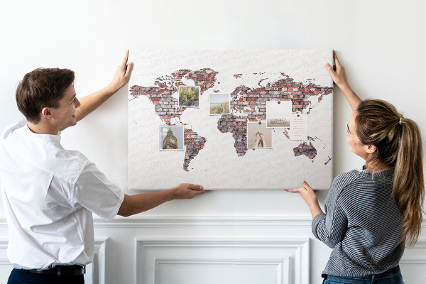 Bacheca in sughero con stampa del mondo su sfondo di muro di mattoni