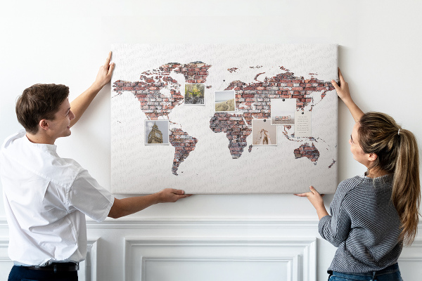 Bacheca in sughero con stampa del mondo su sfondo di muro di mattoni