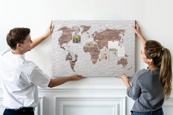 Lavagna di sughero con stampa mappa del mondo su sfondo di muro di mattoni