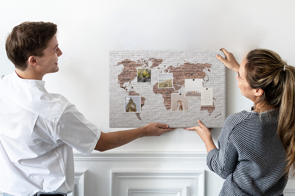 Lavagna di sughero con stampa mappa del mondo su sfondo di muro di mattoni