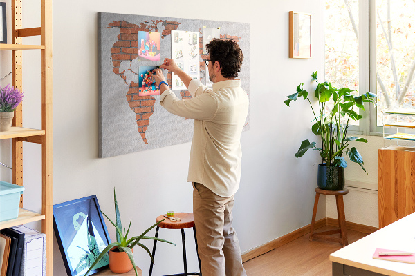 Lavagna di sughero con mappa del mondo su muro di mattoni