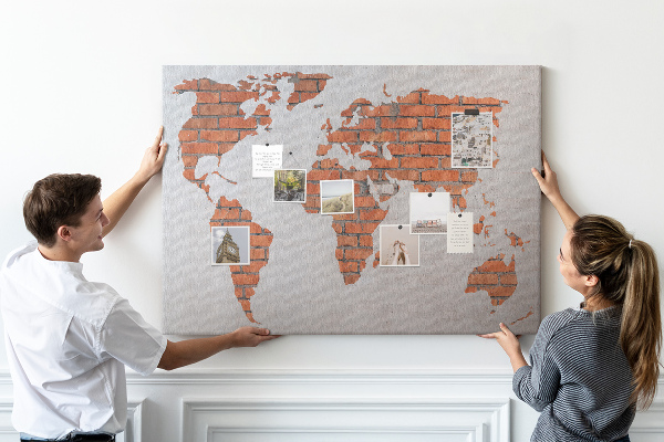 Lavagna di sughero con mappa del mondo su muro di mattoni