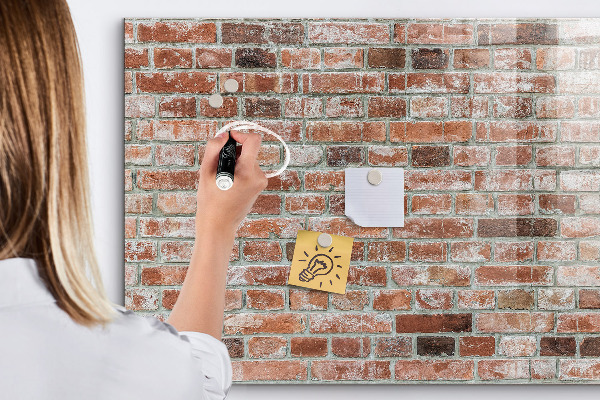 Lavagna magnetica con pennarelli Pannello fotografico su un muro di mattoni