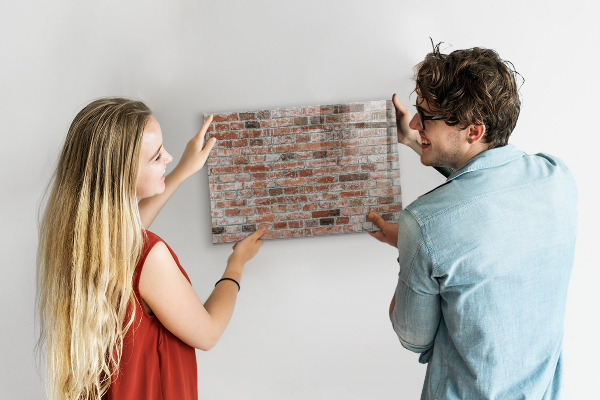 Lavagna magnetica con pennarelli Pannello fotografico su un muro di mattoni